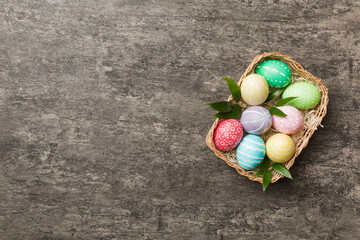 Multi colors Easter eggs in the woven basket on colored background . Pastel color Easter eggs. holiday concept with copy space