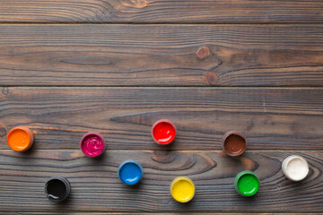 jars with gouache of different colors on Colored background. hobby painting. Top view with empty...