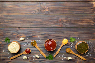 Different sauces in spoons on table background, flat lay top view