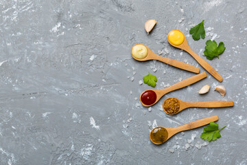 Different sauces in spoons on table background, flat lay top view