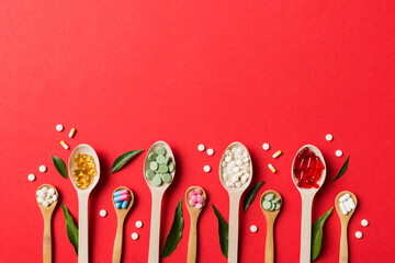 Top view Variety of vitamin and mineral pills in wooden spoon on Colored background. Top view of assorted pharmaceutical medicine pills. Dietary supplement healthcare product