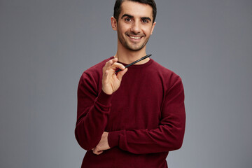 handsome man in a red sweater pen in hand posing self confidence Gray background