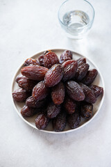 Medjoul dates in a white plate on a gray background. Overhead view.