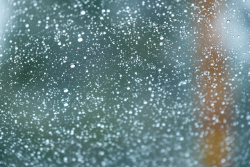Raindrops on a window with a blurry  green background 