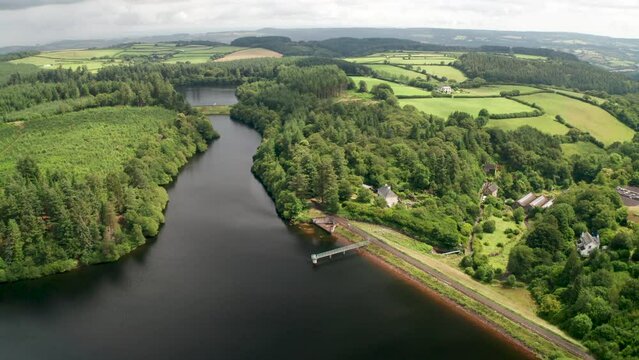 Water catchment reservoir next to valley revealing a dam and farm buildings