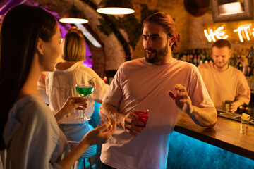 Couple with cocktails talking near counter