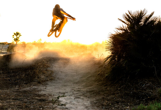 Young mountain biker jumps in a windy and dusty sunset in Spain