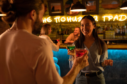 Cheerful Asian woman chatting with man in bar