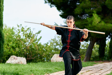Woman in uniform practicing martial arts with a stick