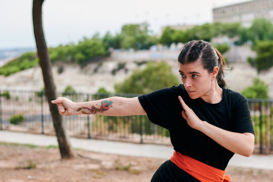 Woman with a tattoo training martial arts in a park
