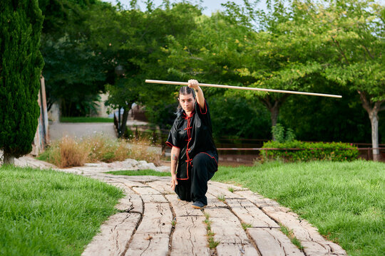 Woman training kung fu with a stick in a park