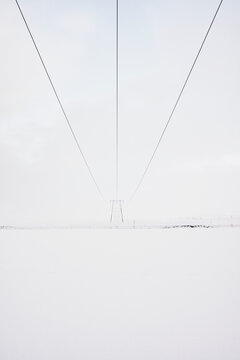 Electric tower on snowy land in countryside