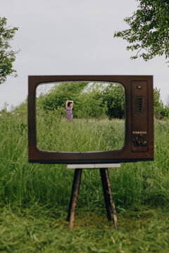 Girl in old television frame box outdoors