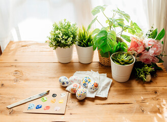 Handmade easter eggs painted. Brushes and paints with flowers and plants. Happy easter concept on a wooden background.