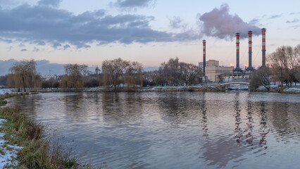 Naklejka premium Power station with reservoir in winter. Beautiful seaside winter sunset with a smoking factory chimney.