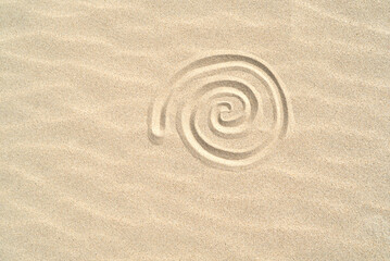 Fototapeta na wymiar Spiral shell drawn on the sand on the beach top view with copy space