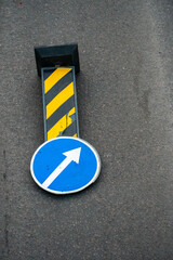 A road sign indicating the need to bypass an obstacle from the right side lies on the carriageway...