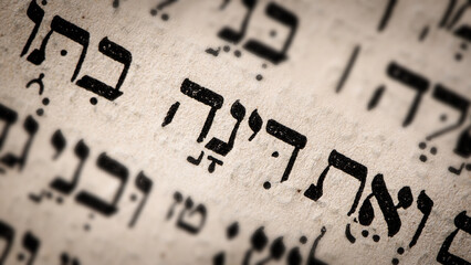 Hebrew word in Torah page. English translation is name Dinah. Daughter of Jacob and Leah. Selective focus. Closeup.