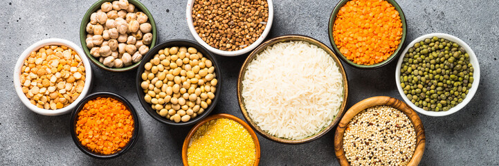 Gluten free cereals. Different bowls with rice, buckwheat, corn, lentils, soy beans and quinoa at stone table.Long banner format.