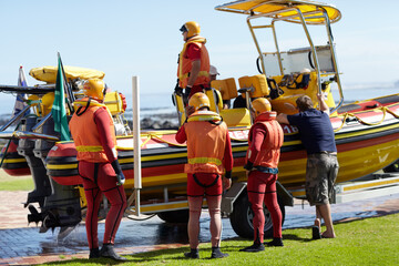 Getting ready to head out. Full length shot of a group of lifeguards preparing to go out to sea on...