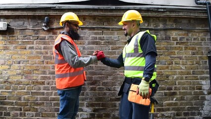 friendly, happy, smiling construction workers greeting and shaking hands.