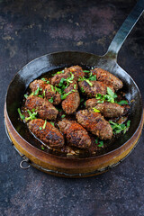 Traditional Croatian cevapcici spicy meat ball rolls with parsley and onion served as close-up in a skillet
