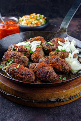 Traditional Croatian cevapcici spicy meat ball rolls with cabbage carrot salad and hot ajvar sauce served as close-up in a rustic skillet