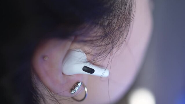 Woman Inserts a Wireless Earphone Into Her Ear Closeup