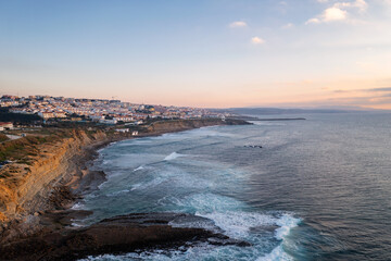 Ericeira drone aerial view on the coast of Portugal with surfers on the sea at sunset