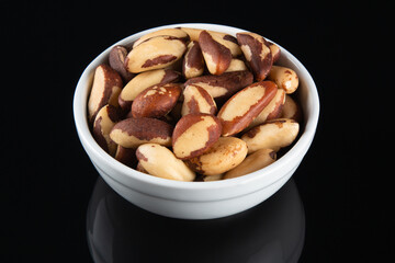 Brazil nuts in white bowl on black background