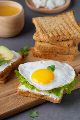 Sandwiches with curd cheese, fried egg, avocado and herbs