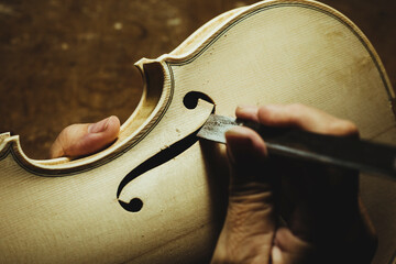 Unrecognized luthier creating a violin and using tools - obrazy, fototapety, plakaty