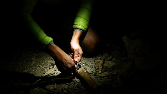 Close up of man's hands lighting fire with flint stone.