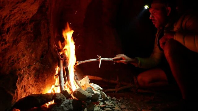 Young man lighting a campfire during camping trip.