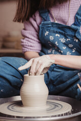 Woman hands working on pottery wheel and making a pot.