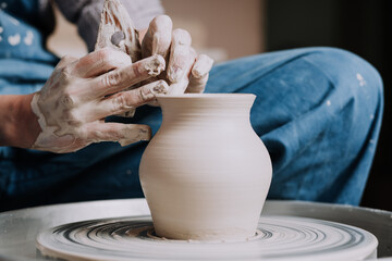 Woman hands working on pottery wheel and making a pot.