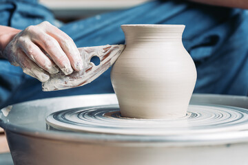 Woman hands working on pottery wheel and making a pot. - obrazy, fototapety, plakaty