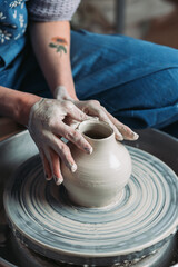 Woman hands working on pottery wheel and making a pot.