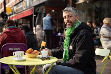 portrait d'un homme de 50 ans souriant qui prend son petit déjeuner à la terrasse d'un café au...