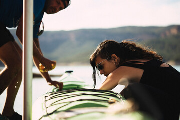 Woman and man servicing a kayak on a pier.