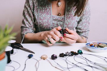 Woman hands making handmade gemstone jewellery, home workshop. Women artisan creates jewellery. Art, hobby, handcraft concept