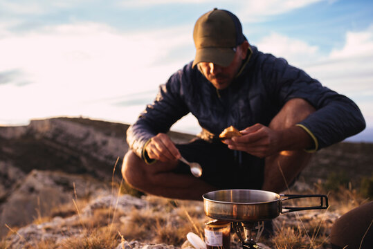 Front view of man cooking during a camping trip in the mountain.
