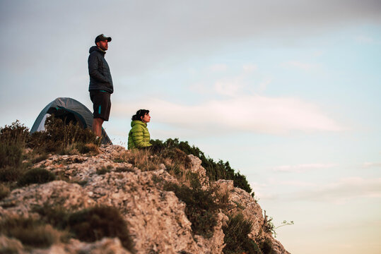 Woman and man sitting on the cliff looking out over the landscape.
