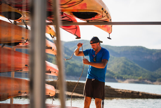 Man with cap doing maintenance work at a kayak rental company.