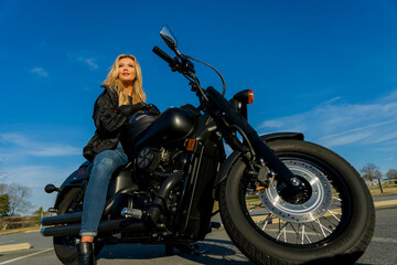 A Lovely Blonde Model Enjoys The Outdoor Weather While Posing With Her Motorcycle