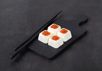 Mini light appetizer, Cream cheese jelly with red sockeye caviar on a serving board. Dark gray background
