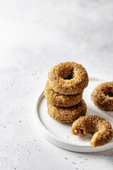 Delicious sugar coated donuts on a plate on white textured background