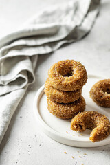 Delicious sugar coated donuts on a plate on white textured background with napkin