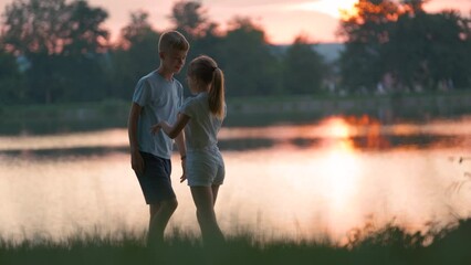 Happy siblings hugging lovingly in summer park. Young children brother and sister embracing each other outdoors. Family love and relationship concept
