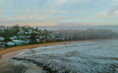 Foggy aerial sunrise over the sea with clouds and sea foam © Merrillie